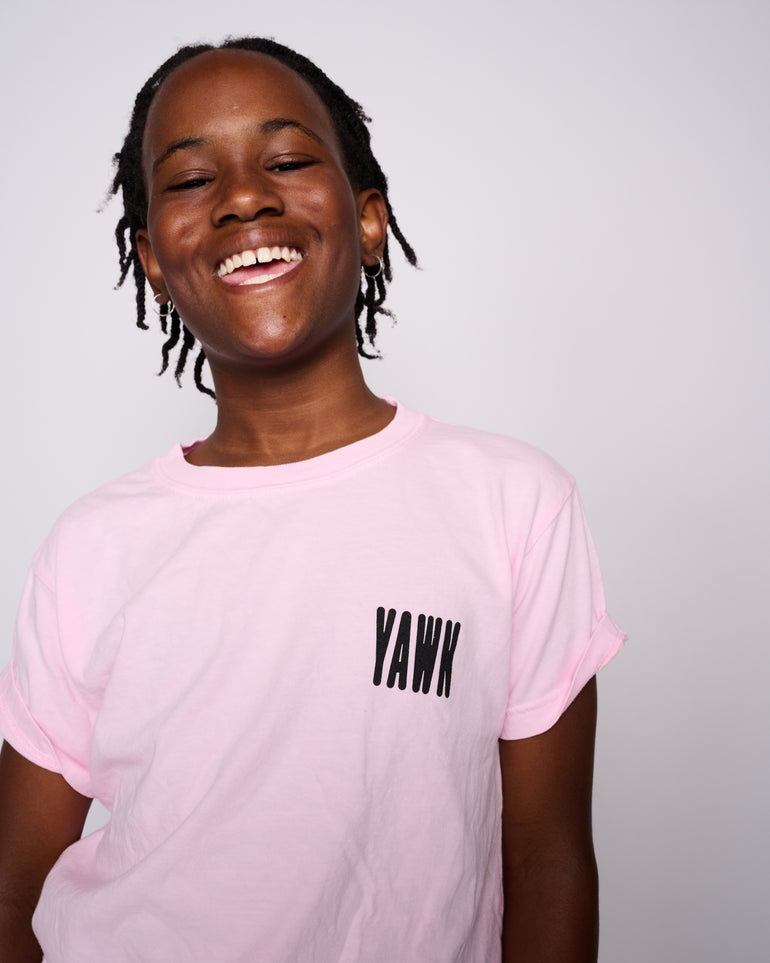 Photo of a kid wearing a pink YAWN tee shirt and smiling at the camera.