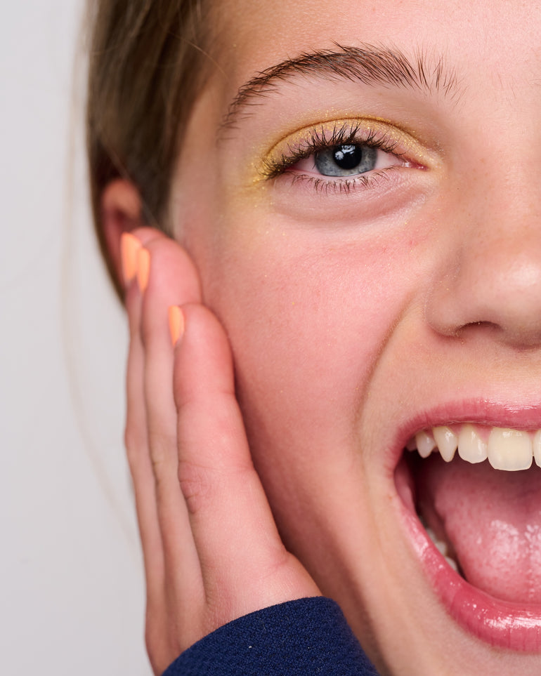 A close up phot of a girl smiling wearing YAWN yellow eyeshadow and YAWN lip gloss