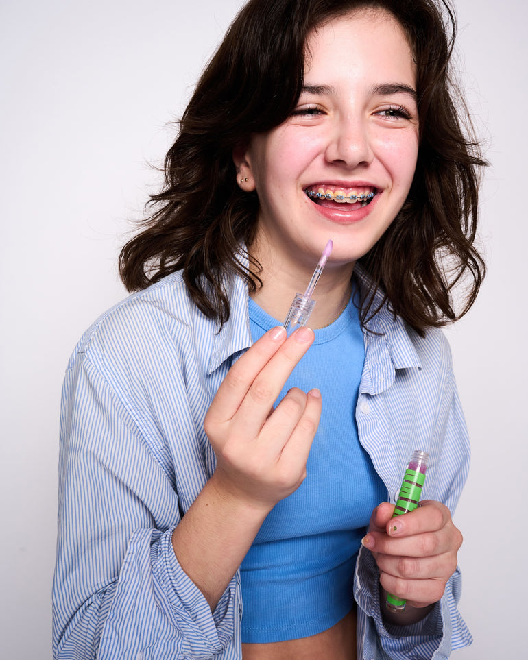 Photo of a kid with braces applying YAWN lip gloss.